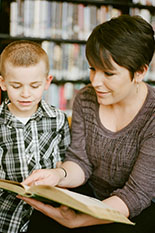 A teacher reads a book with a boy.