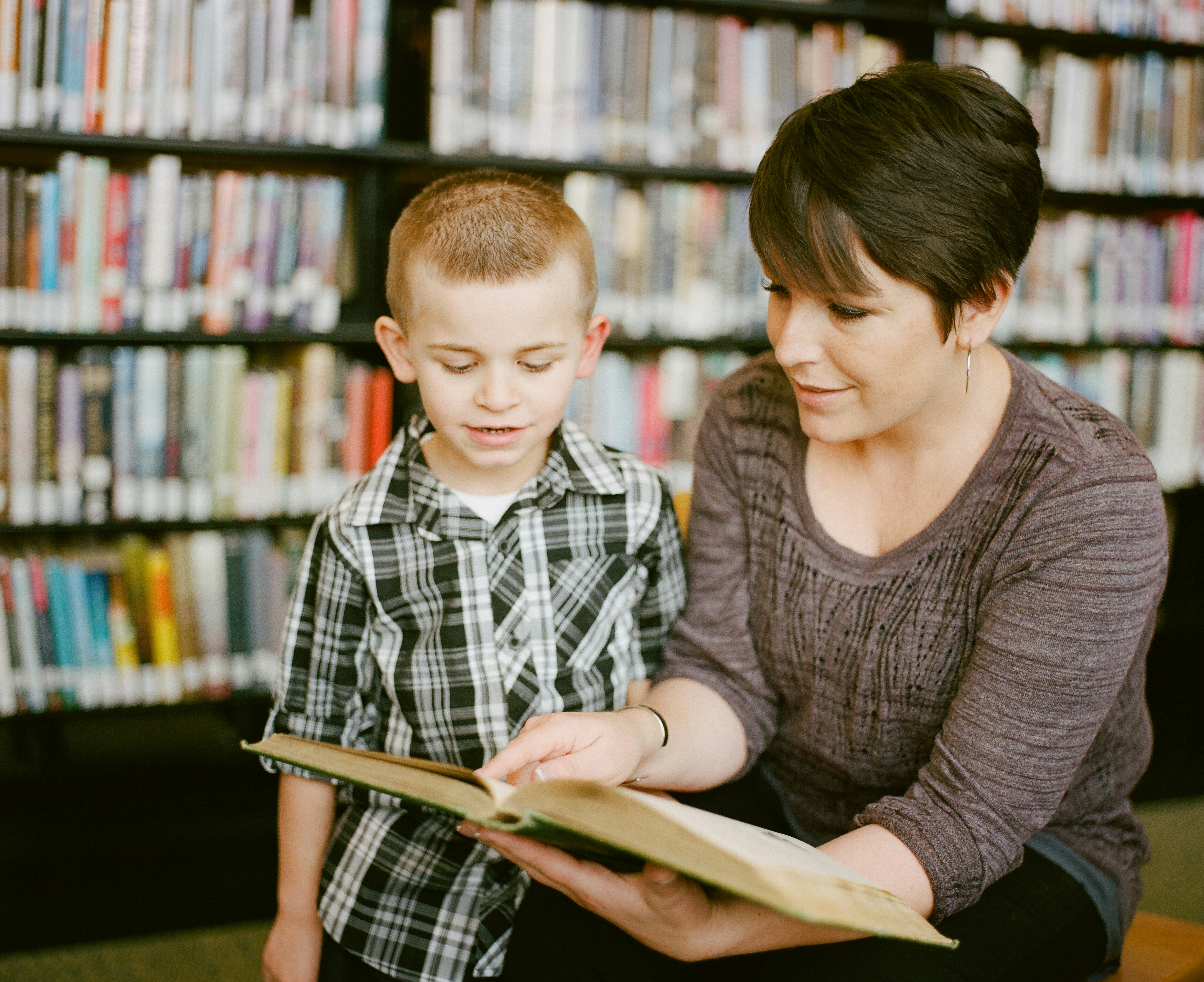 A teacher shows a boy a book.