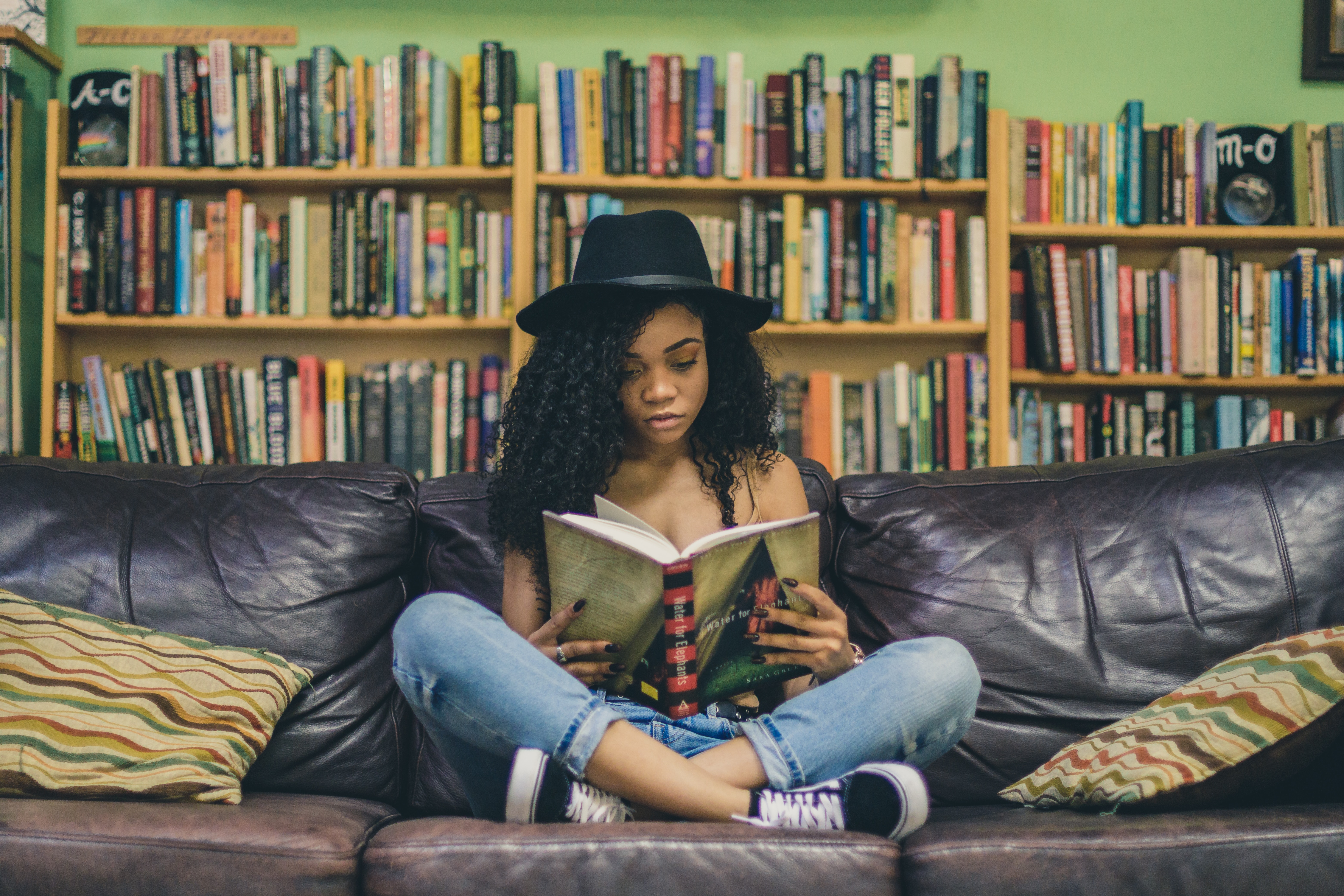 A girl reads a book on a couch.